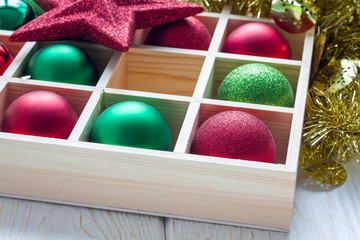 Preparation for Christmas: festive balls in wooden box on white wooden table, horizontal