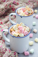 Fototapeta na wymiar Homemade hot chocolate topped with marshmallow in enamel mug, warm scarf on background, vertical