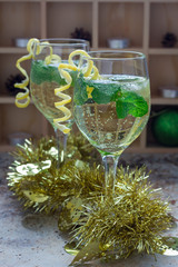 Spritzer cocktail with white wine, mint and ice, decorated with spiral lemon zest, vertical