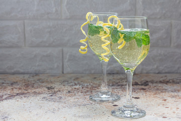 Spritzer cocktail with white wine, mint and ice, decorated with spiral lemon zest, horizontal, copy...