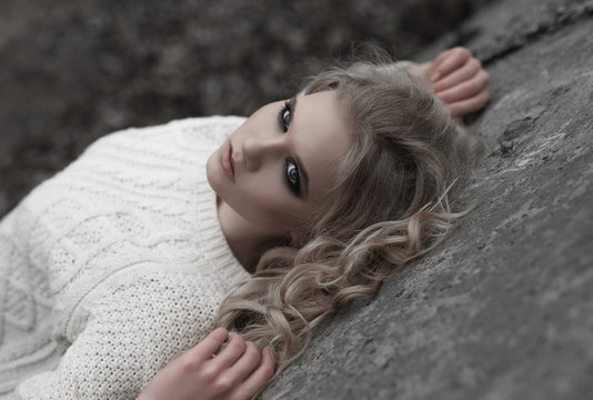 Close up of beautiful young  blonde woman with blue eyes in white pullover. .Winter, spring, outdoor portrait. 
