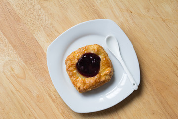 Danish blueberry pie with spoon in white plate on wooden table