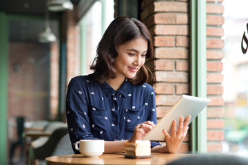 Beautiful cute asian young businesswoman in the cafe, using digi