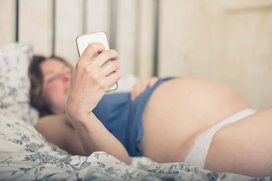 Pregnant woman in bed with smart phone