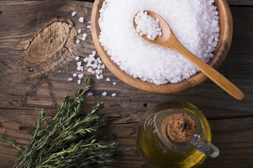 Large White sea salt in a natural wooden bowl with  sprig of fresh rosemary on  simple  background. Selective focus.