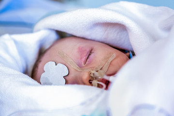 Child in intensive care unit wrapped in blanket, head shot. Shallow depth of field.