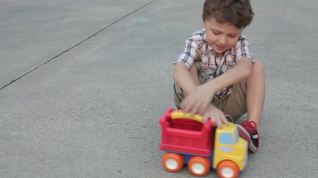 Happy little boy playing with toy car on the road at the day time 