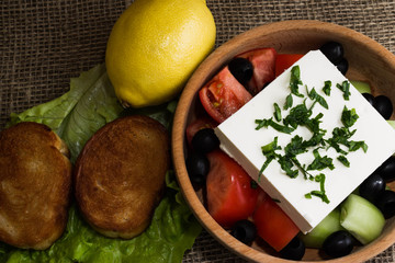 Greek salad with feta cheese and vegetables on wooden plate