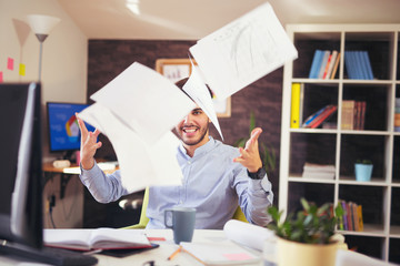 Handsome young smiling businessman working with documents in office