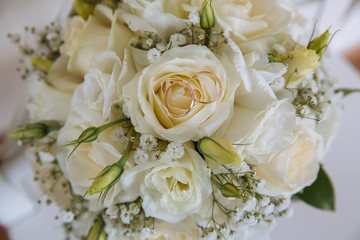 Gold rings on wedding bouquet with white roses