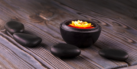 black stones and a candle on wooden background