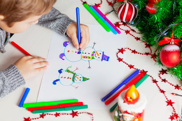 Child draws snowmens.