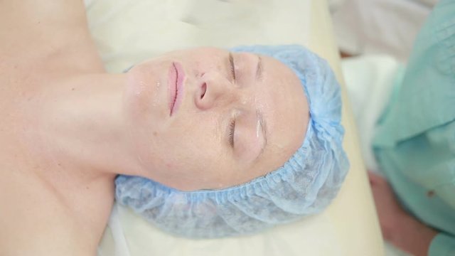 Receiving electric darsonval facial massage procedure. beauty parlor