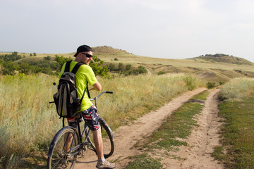 Obraz premium Man on the old bike is traveling across the steppe.