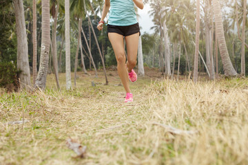 Caucasian woman jogger with beautiful fit body running on grass in tropical forest. Young female...