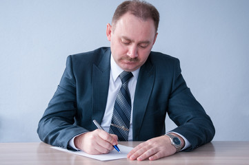 Man in business suit writing on a sheet of paper   