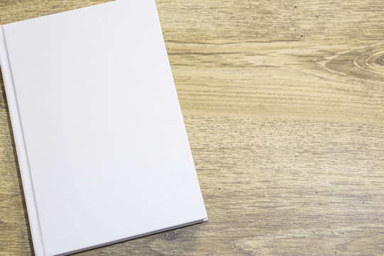 Real 3D hardcover white book on a wood background