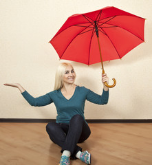 Happy blonde woman with red umbrella sitting on the floor © linavita