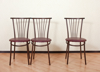 Three of the same chair against the wall