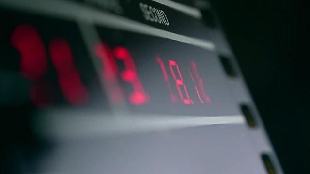 Electronic clock in dark room with red glowing digits. Precise time measurement and digital concepts. 4K video