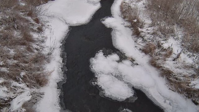 Small River in Winter. A small river flows in the winter, among ice and snow. The water is still not frozen
