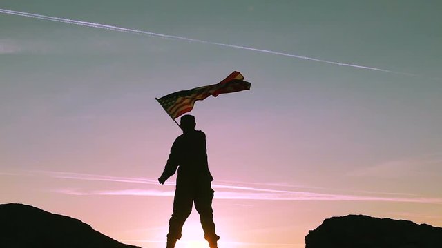 
Soldier waves American Flag Against Sunrise Sky. Slow Motion 

