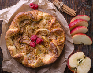 apple pie with cinnamon and raspberry on a wooden table