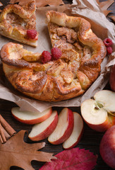 apple pie with cinnamon and raspberry on a wooden table