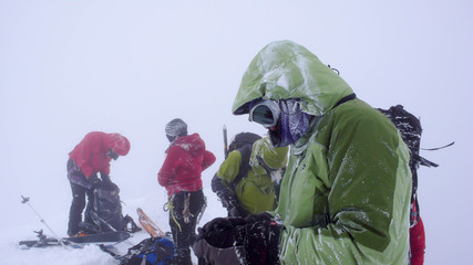 Fototapeta na wymiar a mountain guide and clients on a high alpine peak in the Swiss Alps in the winter during bad weather