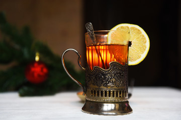 Black tea in glass Cup holder silver spoon next to the old clock on the background of Christmas decorations