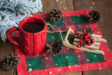 Fototapeta na wymiar cup of tea, fir cones, fir branches in the snow