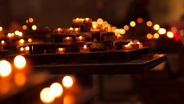 Burning candles on candleholder in the cathedral. Candlelight, sorrow, memory, religion. Closeup real time video.