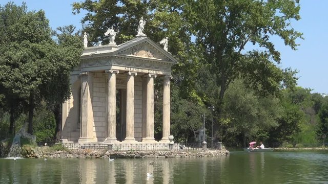 Villa Borghese, Rome, Italy, view of Esculapio temple with pond and tourists on rowing boat. Beautiful historical park in Rome. Travel, tourism destination, Italian history, summer holidays in Europe
