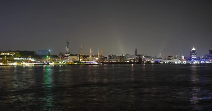Hamburg, Germany - view over river Elbe from south shore to illuminated skyline with museum-ship Rickmer Rickmers and main church St. Michaelis / Michel at night - Timelapse with motion