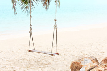Summer, Travel, Vacation concept. Swing hang from coconut palm tree over beach sea in Thailand.