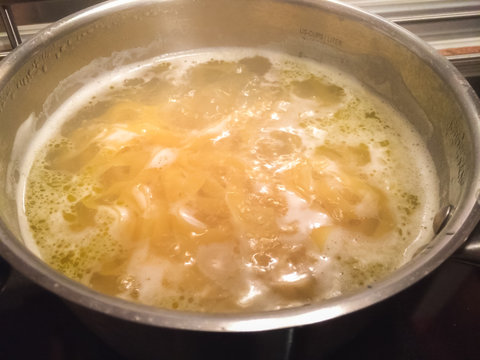 Cooking fettuccine in hot water in pot