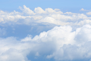 Naklejka na ściany i meble Fluffy white clouds and blue sky seen from airplane.