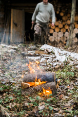 Man kindle a fire in the forest. Rest in the woods on a halt. Hunting Lodge. Autumn, cold and cloudy weather, snow. Bonfire, fire.