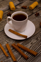 Small white cup of coffee, cinnamon sticks, star anise and cookies on wooden background