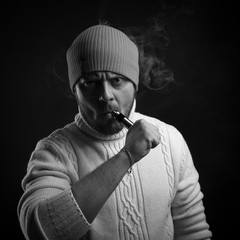 Men with beard vaping on black background in hat