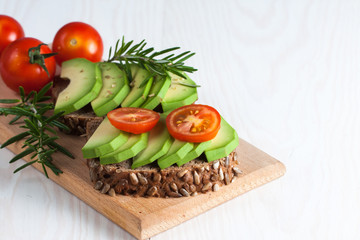 Avocado toast, cherry tomato on wooden background. Breakfast with toast avocado, vegetarian food, healthy diet concept.