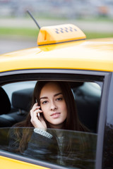 Fototapeta na wymiar Young business woman talking on smartphone sitting in taxi