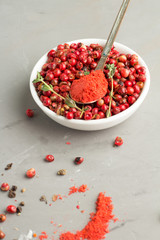 Pink peppercorns on a gray background