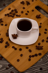 Small white cup of coffee, star anise on wooden background