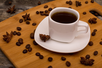 Small white cup of coffee, star anise on wooden background