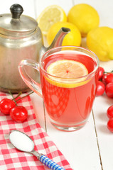 Fruit cherry tea with slice of lemon in mug, old teapot and cherries