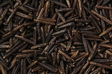 Black rice close-up background. Heap wild brown unpolished rice for vegetarians.