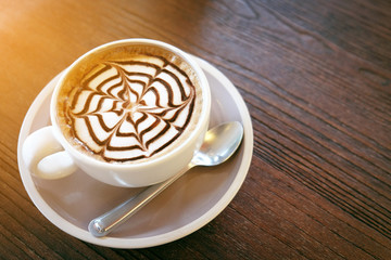 Mocha coffee (also called Caffe Mocha) with wooden saucer. Interior coffee shop. Main ingredients of mocha is chocolate, espresso, hot milk. (vintage tone)
