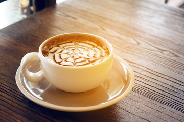 Mocha coffee (also called Caffe Mocha) with wooden saucer. Interior coffee shop. Main ingredients of mocha is chocolate, espresso, hot milk. (vintage tone)