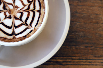 Mocha coffee (also called Caffe Mocha) with wooden saucer. Interior coffee shop. Main ingredients of mocha is chocolate, espresso, hot milk. (vintage tone)